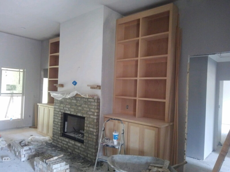 inside image of new construction home build of brick fireplace and custom wooden cabinets and shelves on each side in living area