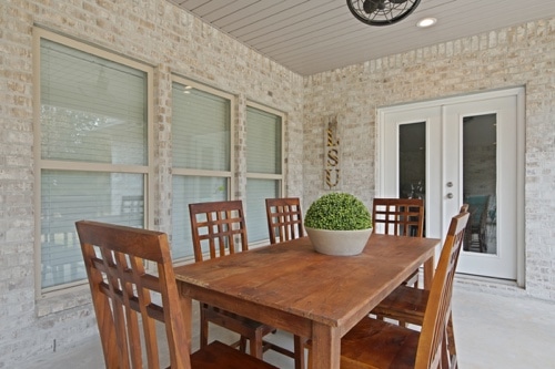 closeup view of wooden dining table in outdoor space near bedroom french doors and LSU sign hanging on outside wall